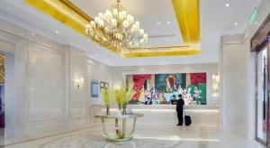 a man standing in a lobby with a painting on the wall at Vienna Hotel Shaanxi Hanzhong Central Square High-Speed Railway Station in Hanzhong +208 photos