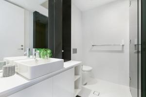 a white bathroom with a sink and a toilet at Ultra modern 2 bdrm in St Leonards Crows Nest - 803NOR in Sydney