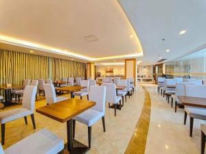 恵州市にあるVienna Hotel Guangdong Huizhou High-Speed North Railway Station Xiaojinkouの木製のテーブルと白い椅子のあるレストラン