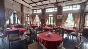 un restaurante con mesas y sillas rojas y ventanas en Sapadia Hotel Parapat, en Parapat