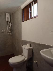 a bathroom with a toilet and a sink and a window at Rock Pool Residence in Tangalle