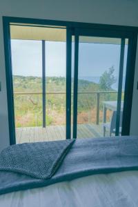 a bedroom with a bed with a view of a deck at Map Of Africa Ocean View Tiny House in Wilderness