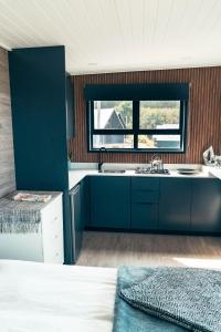 a kitchen with blue cabinets and a sink and a window at Map Of Africa Ocean View Tiny House in Wilderness