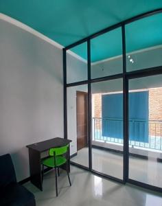Cette chambre comprend une table et une chaise verte. dans l'établissement Homestay keluarga solo or solo's family homestay, à Purwosari