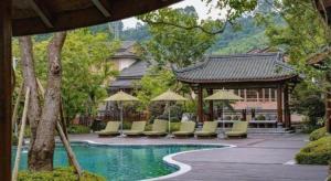 a pool with chairs and umbrellas next to a building at The Mulian Hotel in Dayi