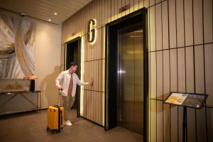 クアラルンプールにあるCeylonz KLCC by Mana-Manaのエレベーターの中で黄色いスーツケースを持った男性