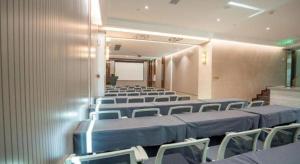 a conference room with rows of chairs and a screen at Tomeet Hotel in Meizhou