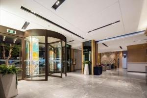 a lobby of a building with glass doors and plants at Echarm Hotel Wuhan Hankou Railway Station Zhuyeshan Metro Station in Wuhan