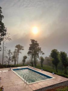une piscine avec le soleil levant en arrière-plan dans l'établissement ATJ The Hideout, à Vagamon