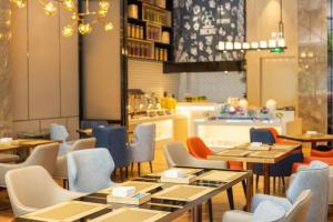 a restaurant with tables and chairs and a counter at Echarm Hotel Shenzhen World Exhibition and Convention Center in Fenghuangwei