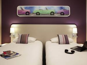 Dos camas en una habitación de hotel con una foto de dos coches. en ibis Styles Montbéliard, en Montbéliard 65 fotos más