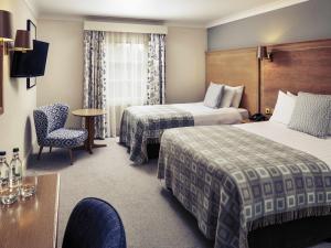 a hotel room with two beds and a table at Mercure Gloucester Bowden Hall Hotel in Gloucester