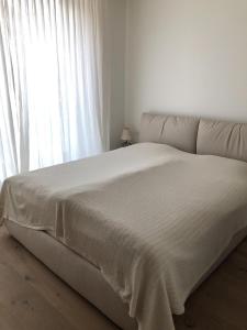 a bed in a white room with a large window at Motta Rotonda in Maloja