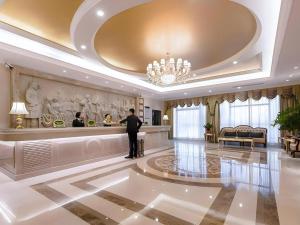 a man standing in a hotel lobby with a counter at Vienna Hotel Chongqing Yongchuan High-Speed Railway Station Xinglong Lake in Yongchuan