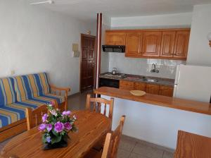 a kitchen and a table with a vase of flowers on it at Apartamentos Las Floritas in Playa de las Americas