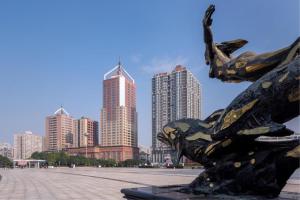 a statue in front of a city with tall buildings at Gold Source Sunshine Hotel in Changsha