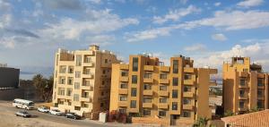 a large building with cars parked in front of it at swahmaya apartments for rent in Sowayma