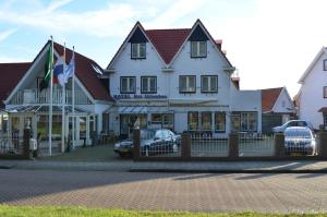 a large white building with cars parked in front of it at Het Uilenbos in De Koog