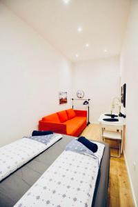 Habitación con 2 camas y sofá naranja en Super Central Cozy 5 BR Shared Apt 10Min Walk to Augarten, en Viena