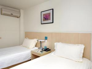 a hotel room with two beds and a desk with a lamp at Jinjiang Inn Shanghai Tongji University in Shanghai +84 photos