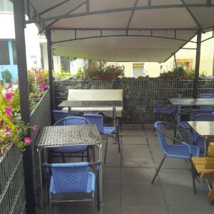 un patio extérieur avec des chaises, des tables et un parasol dans l'établissement Gasthof Zum Burgkrug, à Leuchtenberg