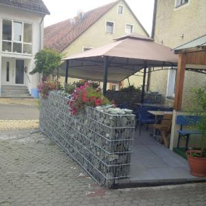 eine Terrasse mit einem Sonnenschirm und einem Tisch mit Blumen in der Unterkunft Gasthof Zum Burgkrug in Leuchtenberg