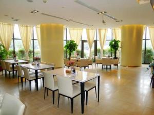 een eetkamer met tafels, stoelen en ramen bij Jinjiang Inn Zhengzhou International Convention Center in Jicheng