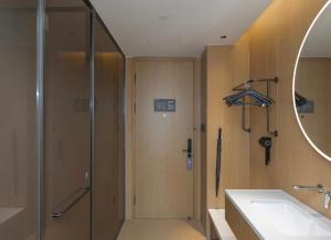 ein Badezimmer mit Dusche, Waschbecken und Spiegel in der Unterkunft JI Hotel Shanghai New International Expo Center Longyang Road in Shanghai + 11 Fotos