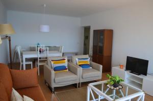 a living room with two chairs and a television at Lila's Beach Apartment in São Roque