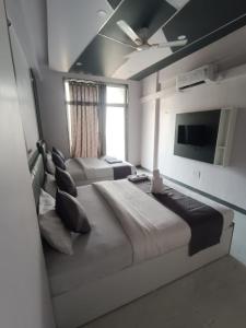 a bedroom with two beds and a flat screen tv at Hotel Majestic Royal, Akkalkot in Akalkot