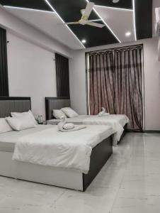 two beds in a room with a ceiling fan at Hotel Majestic Royal, Akkalkot in Akalkot