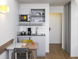 a small kitchen with a table and a microwave at Aparthotel Adagio Access La Défense - Place Charras in Courbevoie