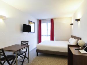 a hotel room with a bed and a table and a desk at Aparthotel Adagio Access La Défense - Place Charras in Courbevoie