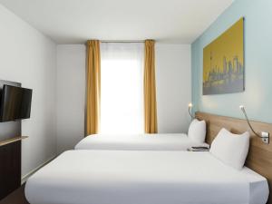 two beds in a hotel room with a window at Aparthotel Adagio Access Paris Clamart in Clamart