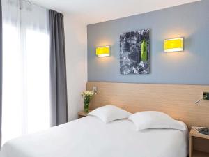 a bedroom with a white bed and a window at Aparthotel Adagio Access Nice Magnan in Nice
