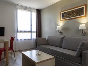 a living room with a couch and a table at Aparthotel Adagio Access Avignon in Avignon