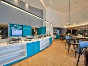 a kitchen with blue cabinets and tables and chairs at Jinjiang Inn Style Ningbo Railway Station in Ningbo