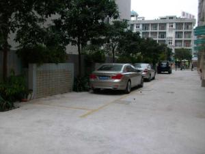 dos autos estacionados en un estacionamiento al lado de un edificio en Jinjiang Inn Dongguan Nancheng Xiping Subway Station, en Dongguan