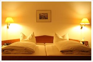 a bedroom with a bed with white pillows and two lamps at Hotel "Die Kupferpfanne" in Donaustauf