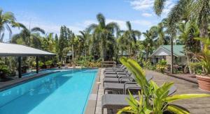 a large swimming pool with lounge chairs and palm trees at Orator Hotel in Siusega