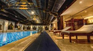 a swimming pool with two hammocks in a building at Tong Que Tai Jinling Hotel Tongling Anhui in Tongling