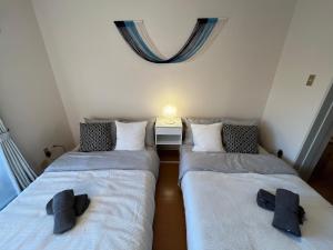 twee bedden in een kleine kamer met een raam bij 伊勢ヒルトップ アパートメント in Ise