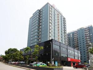 wysoki budynek z samochodami zaparkowanymi przed nim w obiekcie Jinjiang Inn Xianning Yinquan Avenue Hot Spring Hotel w mieście Xianning