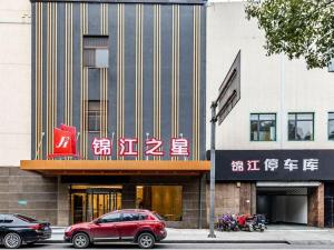 a red car parked in front of a building at Jinjiang Inn Zhangjiagang Yangshe West Street Pedestrian Street in Zhangjiagang