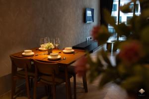a wooden table with chairs and wine glasses on it at Rumaho Upton by Elica Kuching in Kuching
