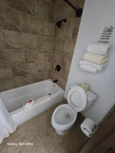 y baño con aseo y bañera con toallas. en Enchanted Escape Lodge, en Eagle Nest