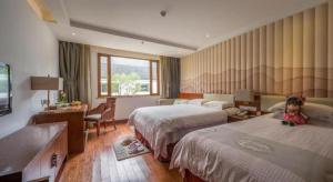 a hotel room with two beds and a teddy bear on the floor at Dongya Hotel in Jiuhuajie +167 photos