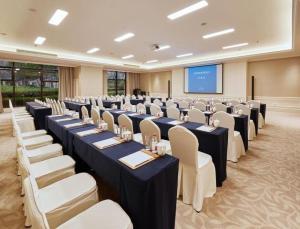een conferentieruimte met tafels en stoelen en een scherm bij Donghai Xianhucheng Huanglong Hotel in Xinliangting +226 foto's
