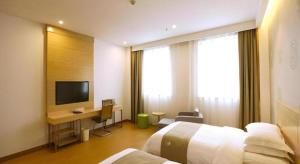 a hotel room with two beds and a desk and a television at GreenTree Inn Xi'an Terracotta Warriors Huaqing Pool Metro Station in Xi'an