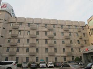 een groot gebouw met auto's geparkeerd voor het bij Jingjiang Inn Zhengzhou Hongqi Road in Zhengzhou